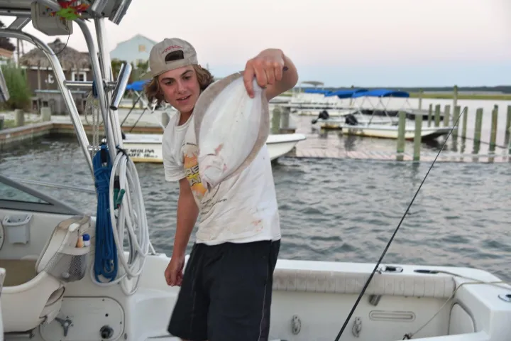a man holding a fish on a boat