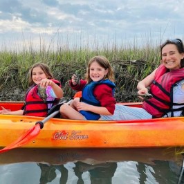 a small child smiling in front of a body of water