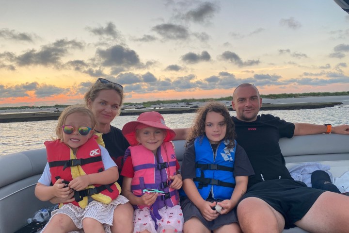 Family on a boat at sunset, wearing life vests.